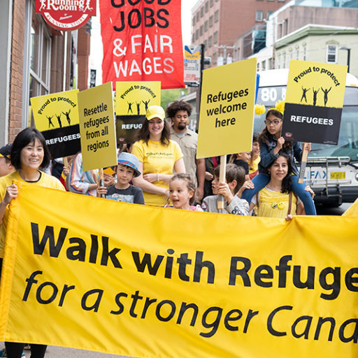 People carrying the Walk with Refugees banner and signs
