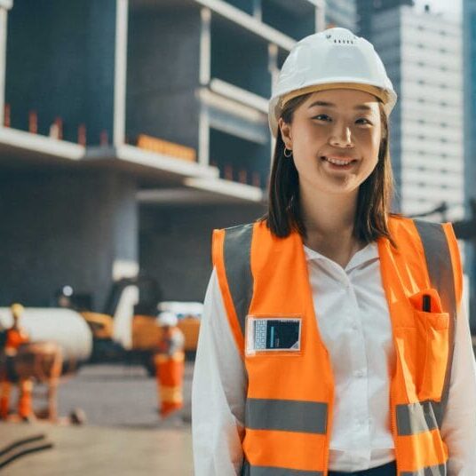 A skilled immigrant engineer woman smiling in front of a construction site