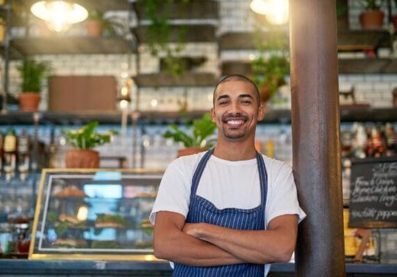 A male immigrant business owner in front of his shop