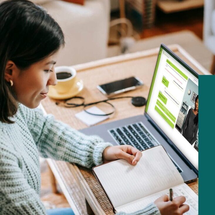 Woman taking notes in front of laptop