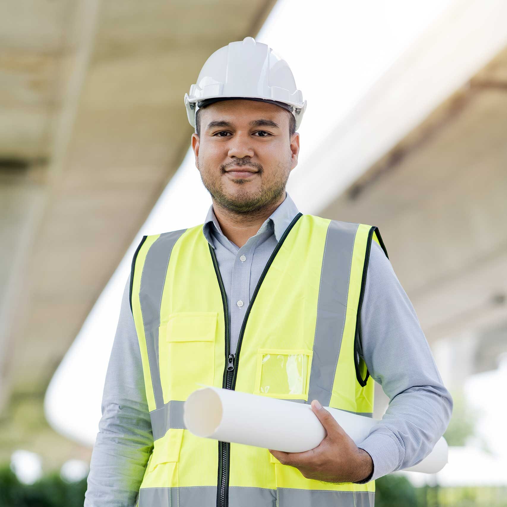 Immigrant male engineer smiling and standing under a bridge